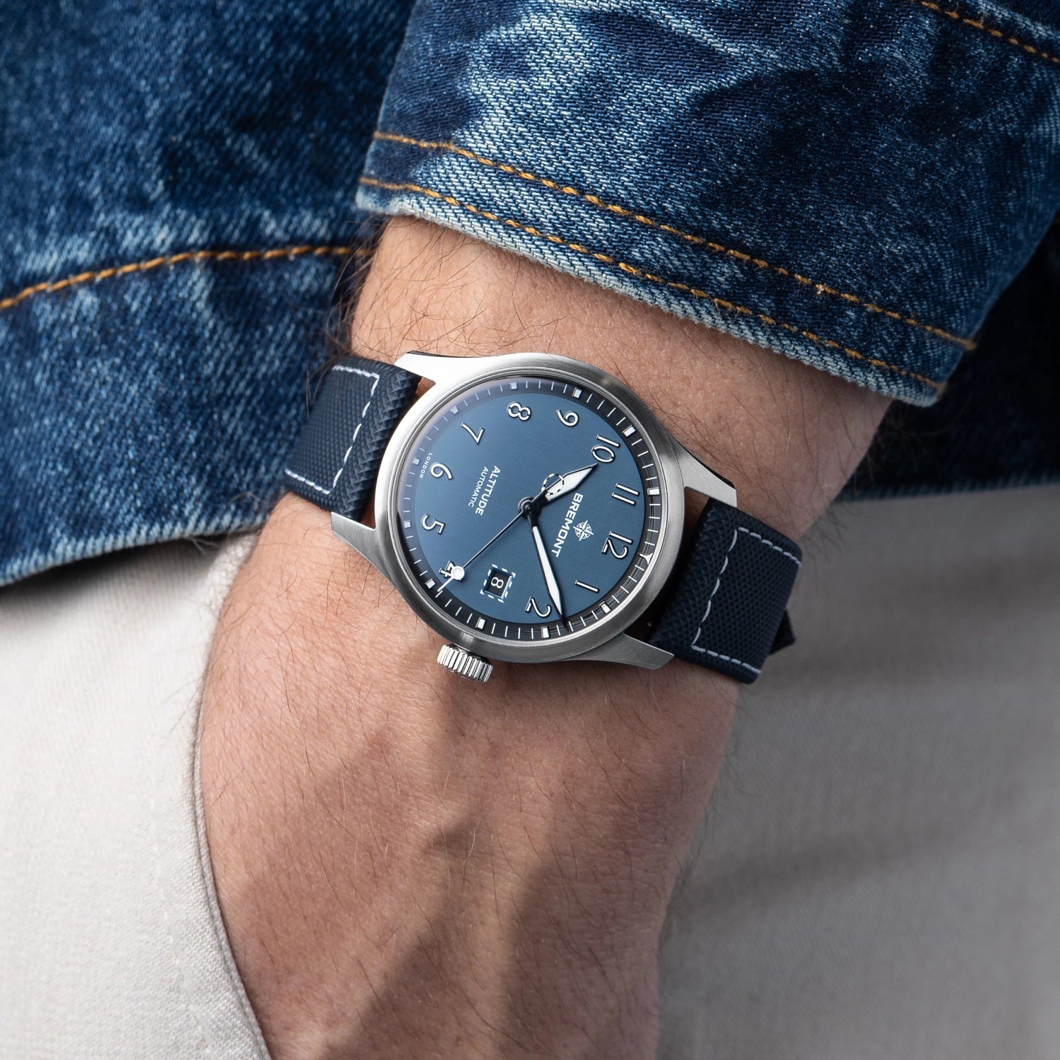 Wrist wearing a blue watch with a denim background Bremont